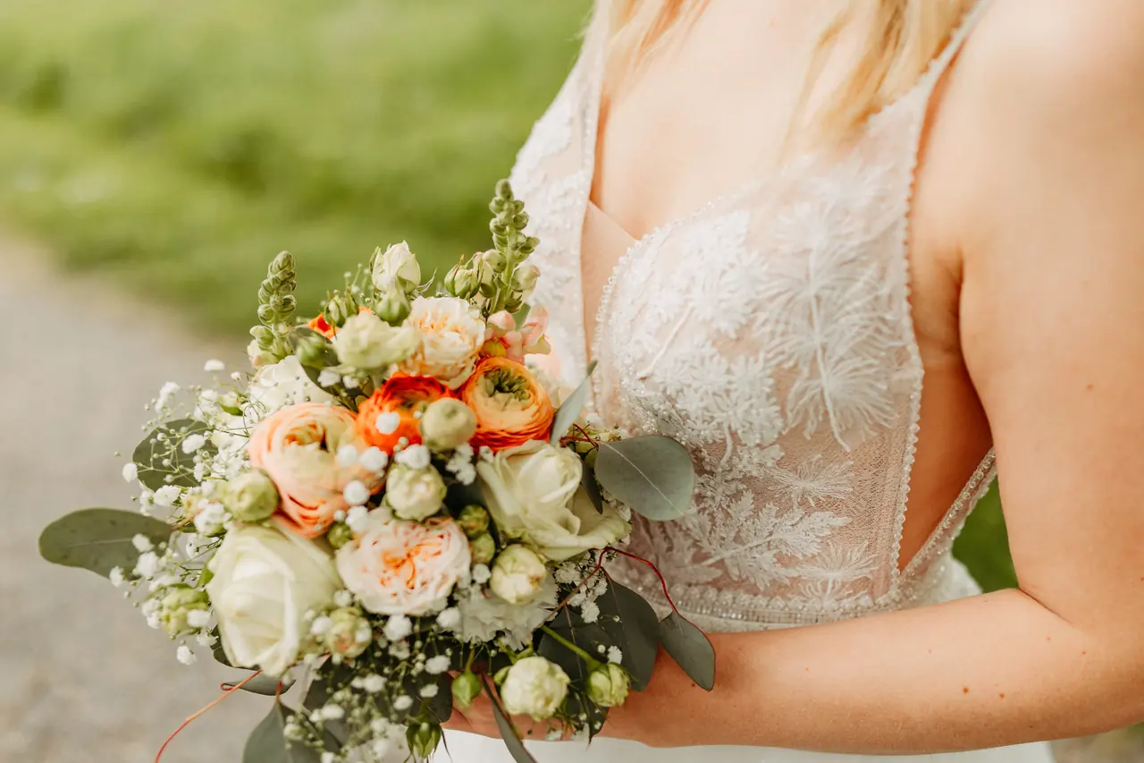 Braut hält einen Brautstrauß mit Rosen in Pfirsich und Weiß