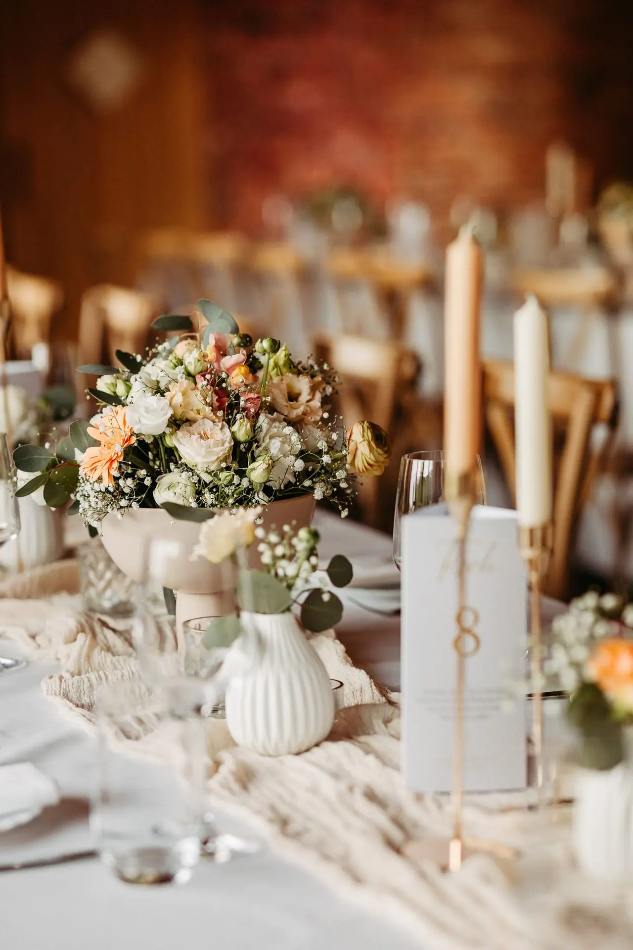 Centerpiece mit Blumen in Pastelltönen, Kerzen und Menükarte auf einer Hochzeitstafel