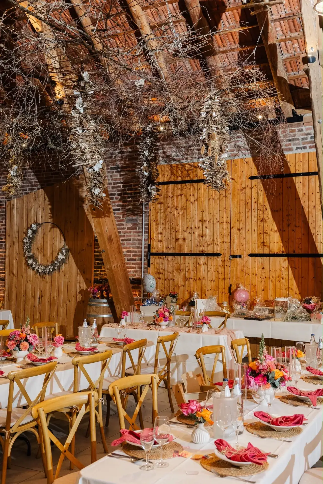 Festlich gedeckte Tafeln in einer Scheune mit pinken Servietten und Blumen von Stil-Echt