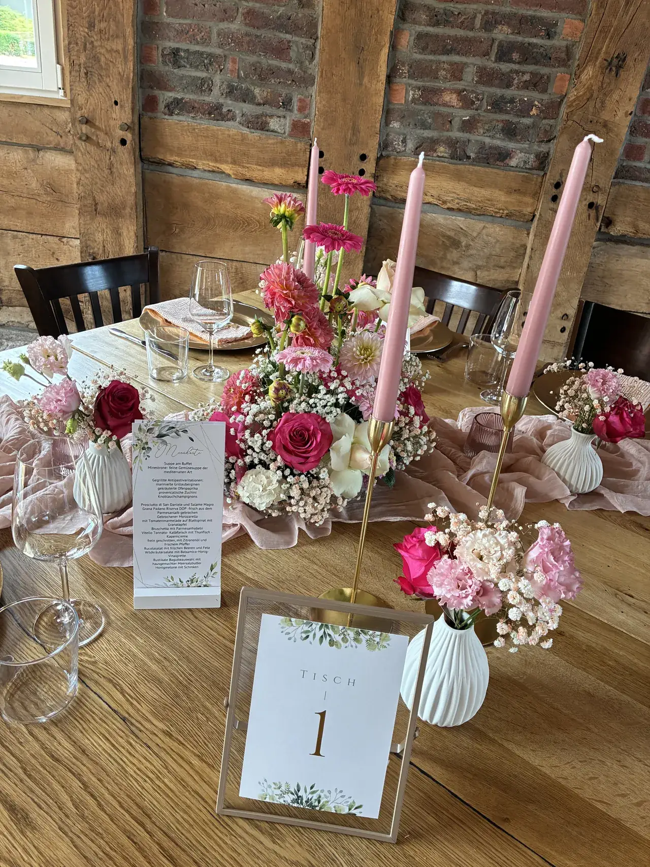 Tischdeko mit Tischnummer, pinken Blumen und rosa Stabkerzen