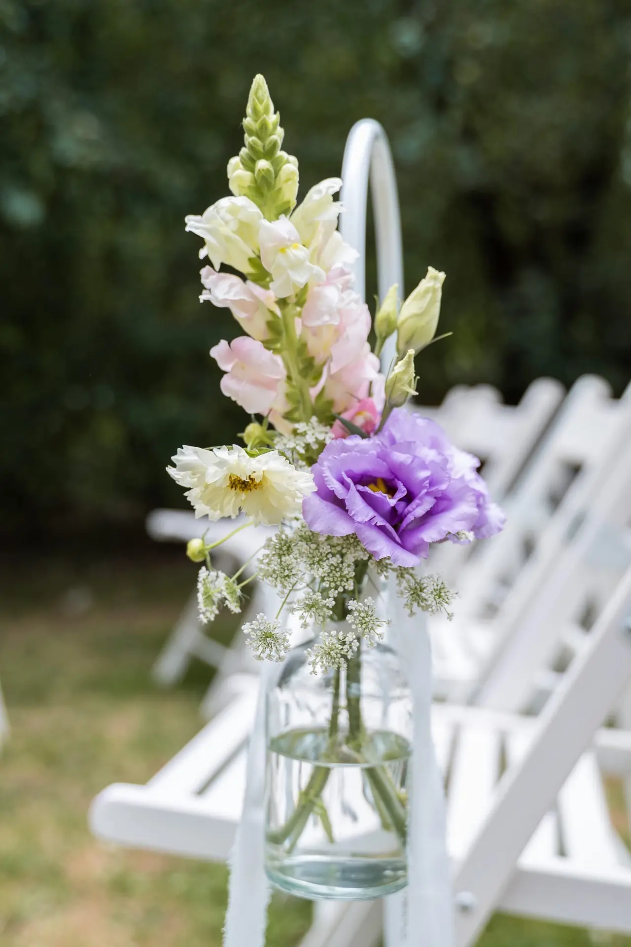 Blumen im Glas als Stuhldekoration am Gang einer freien Trauung